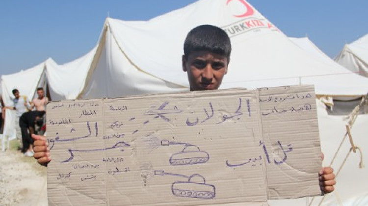 Un nen refugiat a Turquia mostra missatges que denuncien la repressió del règim de Bashar al-Assad